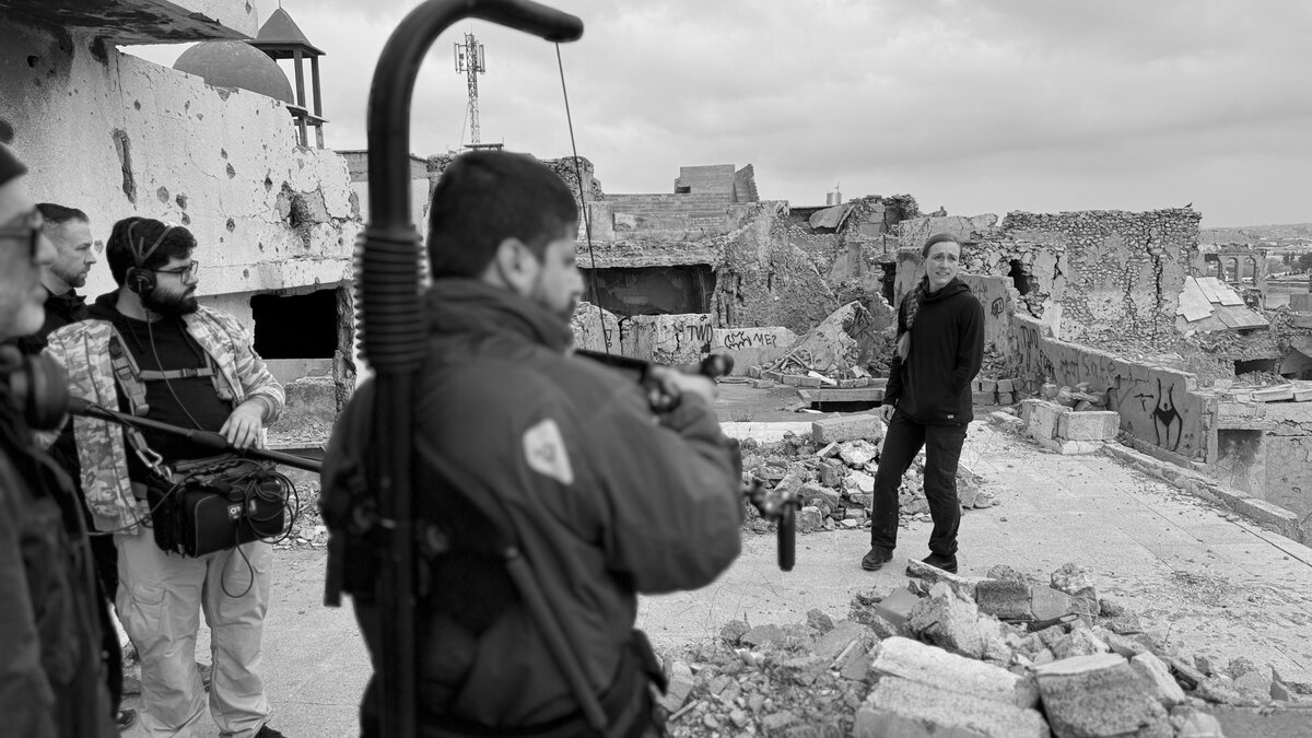 Crew walking through the ruins of Mosul with a security escort