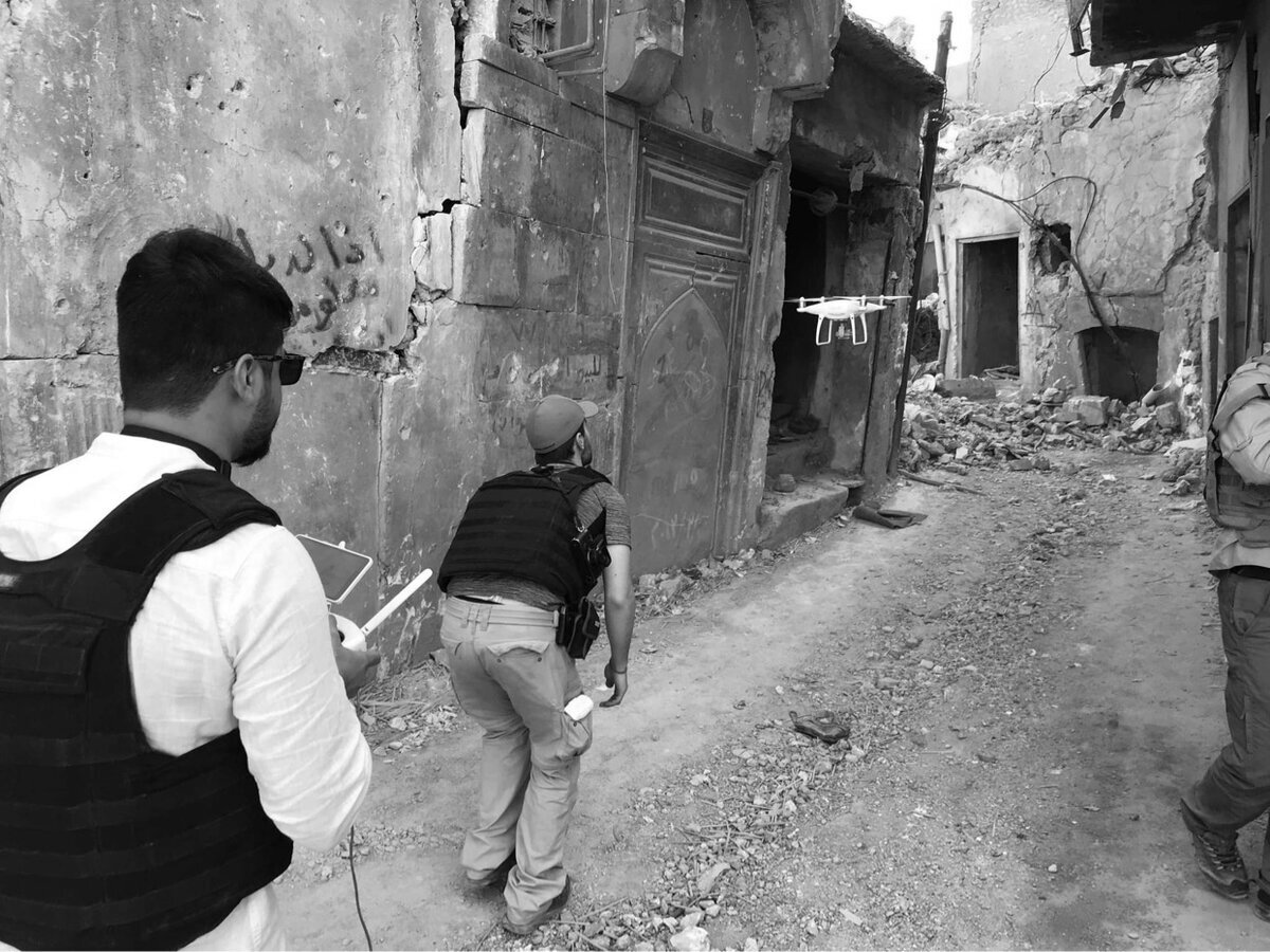 Drone operator walking through a ruined alley in Mosul
