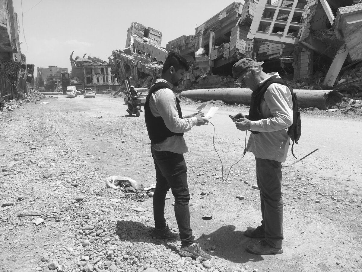 Two crew members with drone equipment in a ruined street