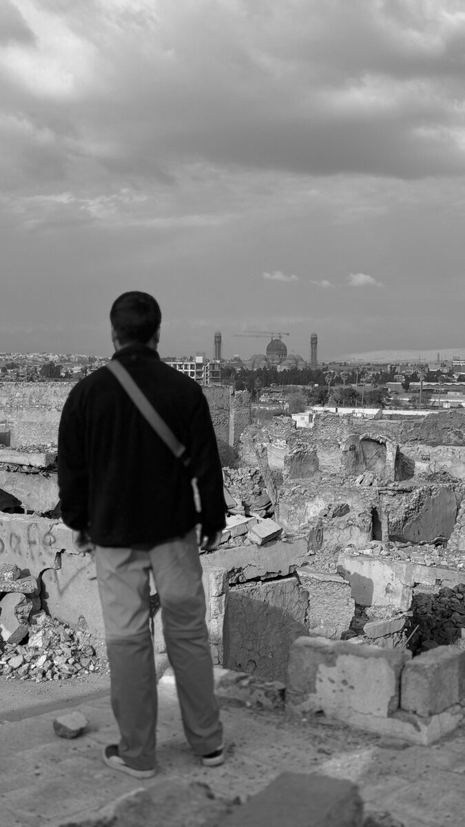 Silhouette of a crew member overlooking bombed-out buildings