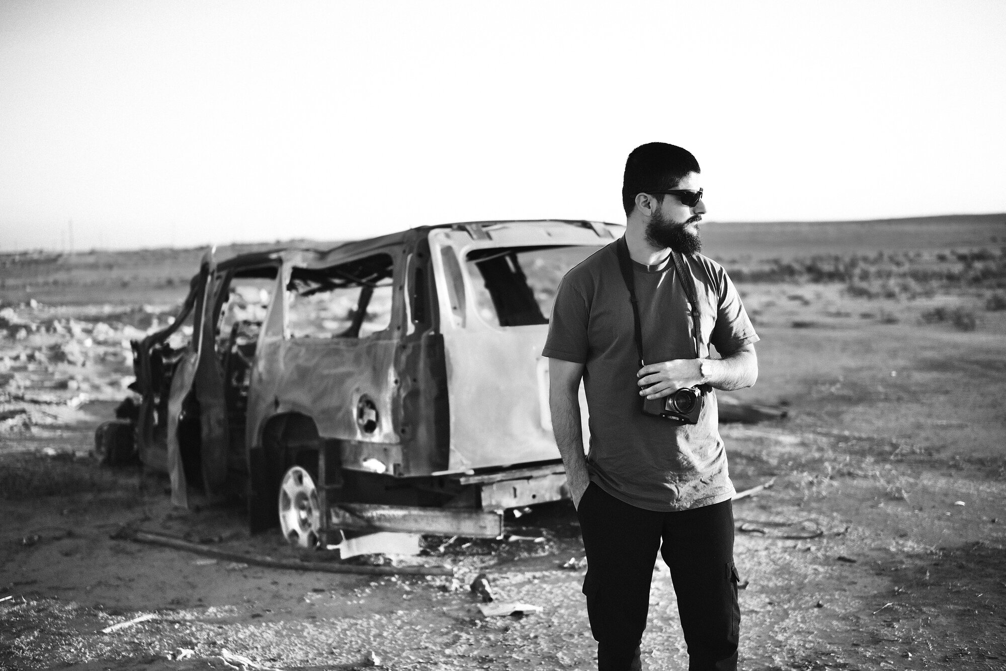 Ayar Rasool standing beside a burnt-out vehicle in Iraq